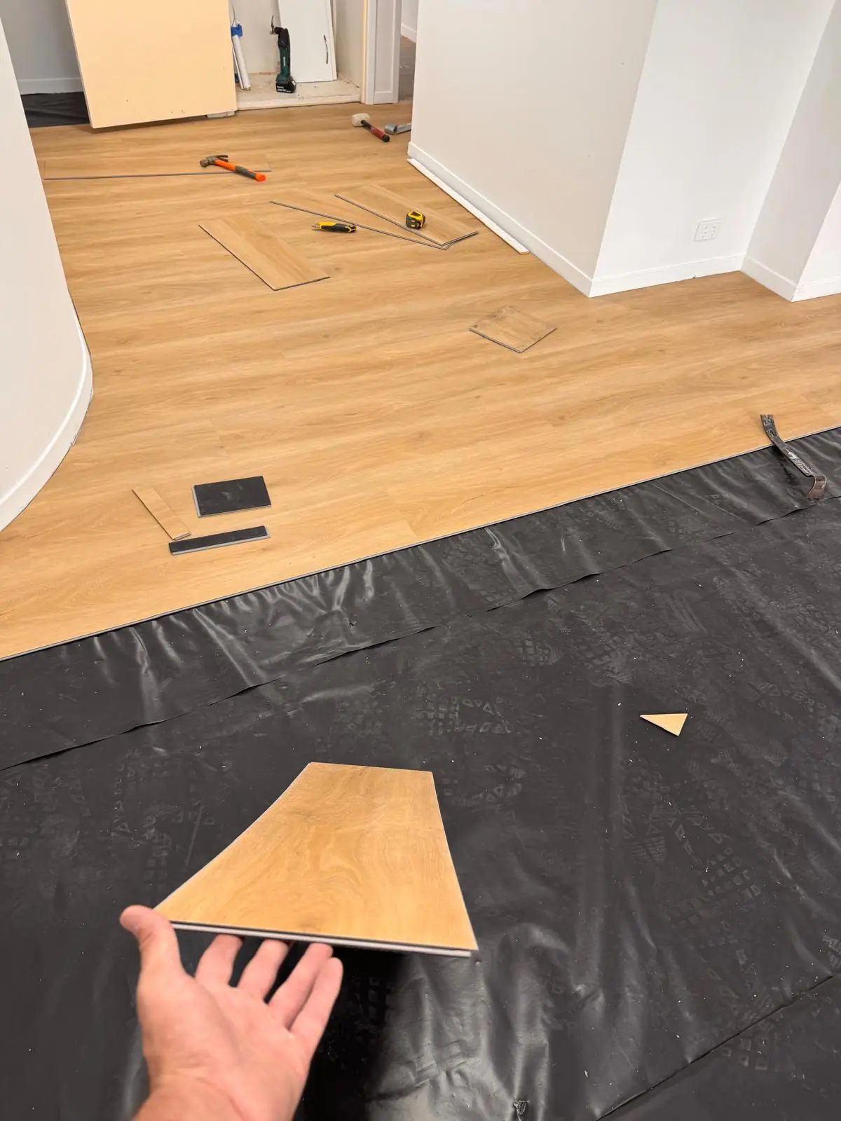 Flooring board being positioned on black underlay beside a partly laid floating floor