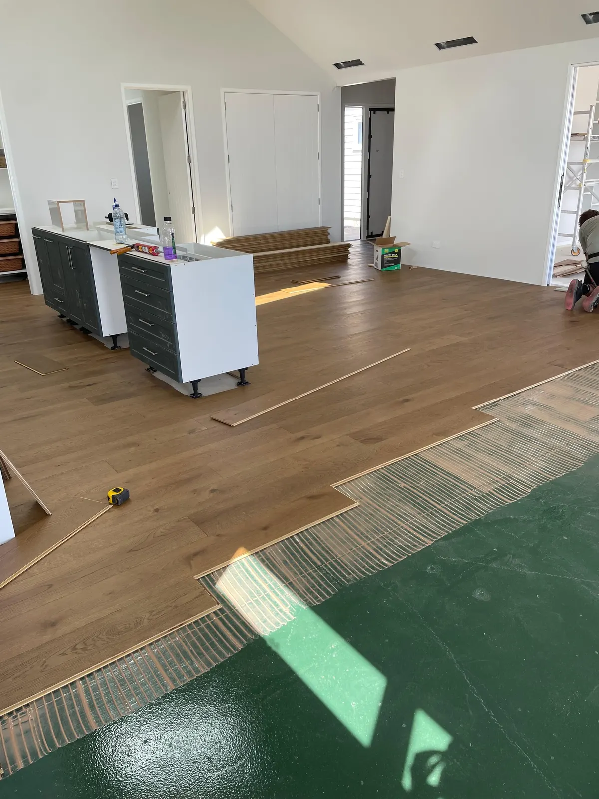 Glue-down timber flooring being installed over a prepared slab with moisture membrane