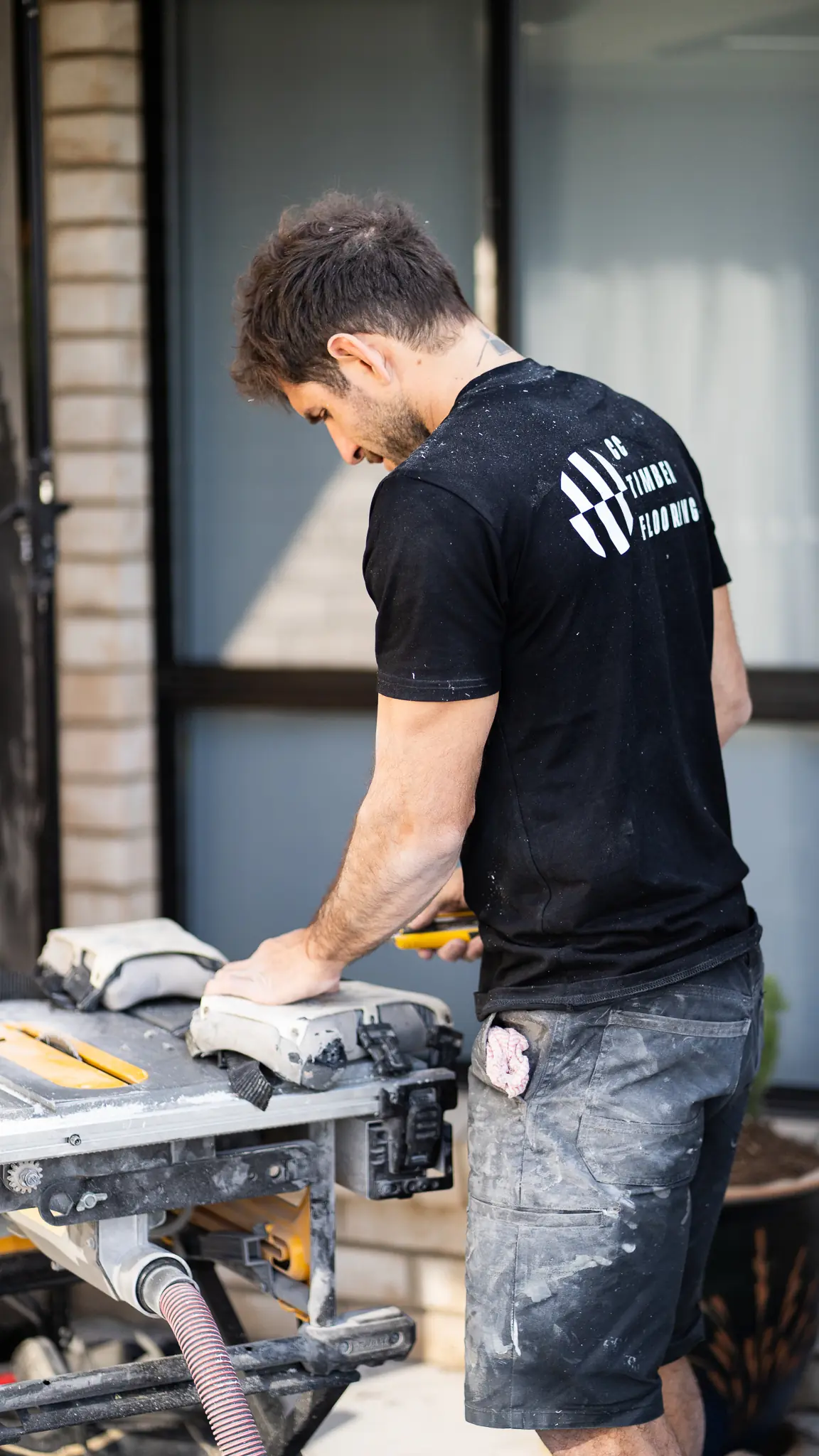 Fabrizio cutting a board at a table saw outside a Gold Coast job site