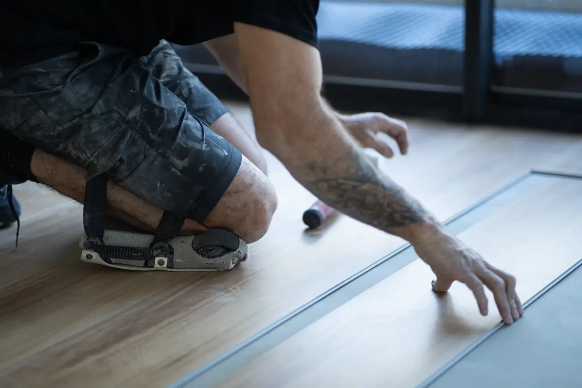 Installer on knee pads positioning the next board against the last row