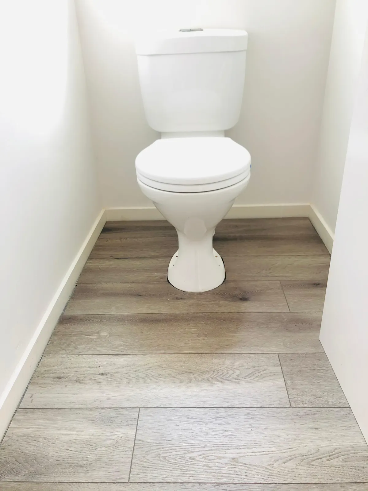 Laminate flooring finished with white skirting in a small room