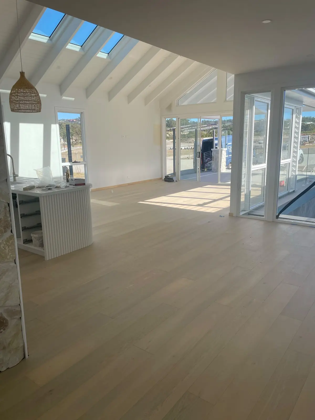 Pale timber floor through an open-plan living area with a raked ceiling and skylights