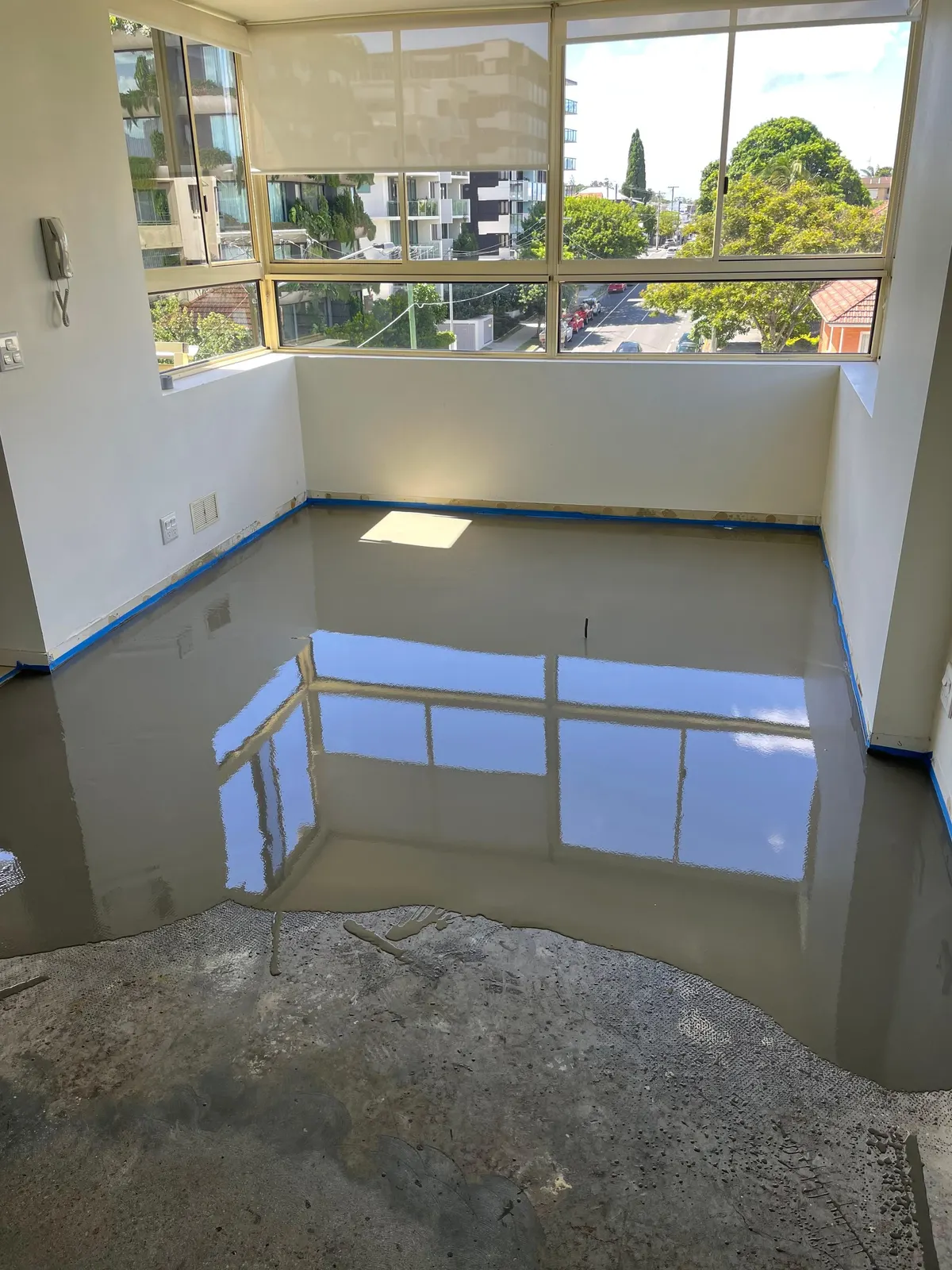 Self-levelling compound poured across an apartment floor