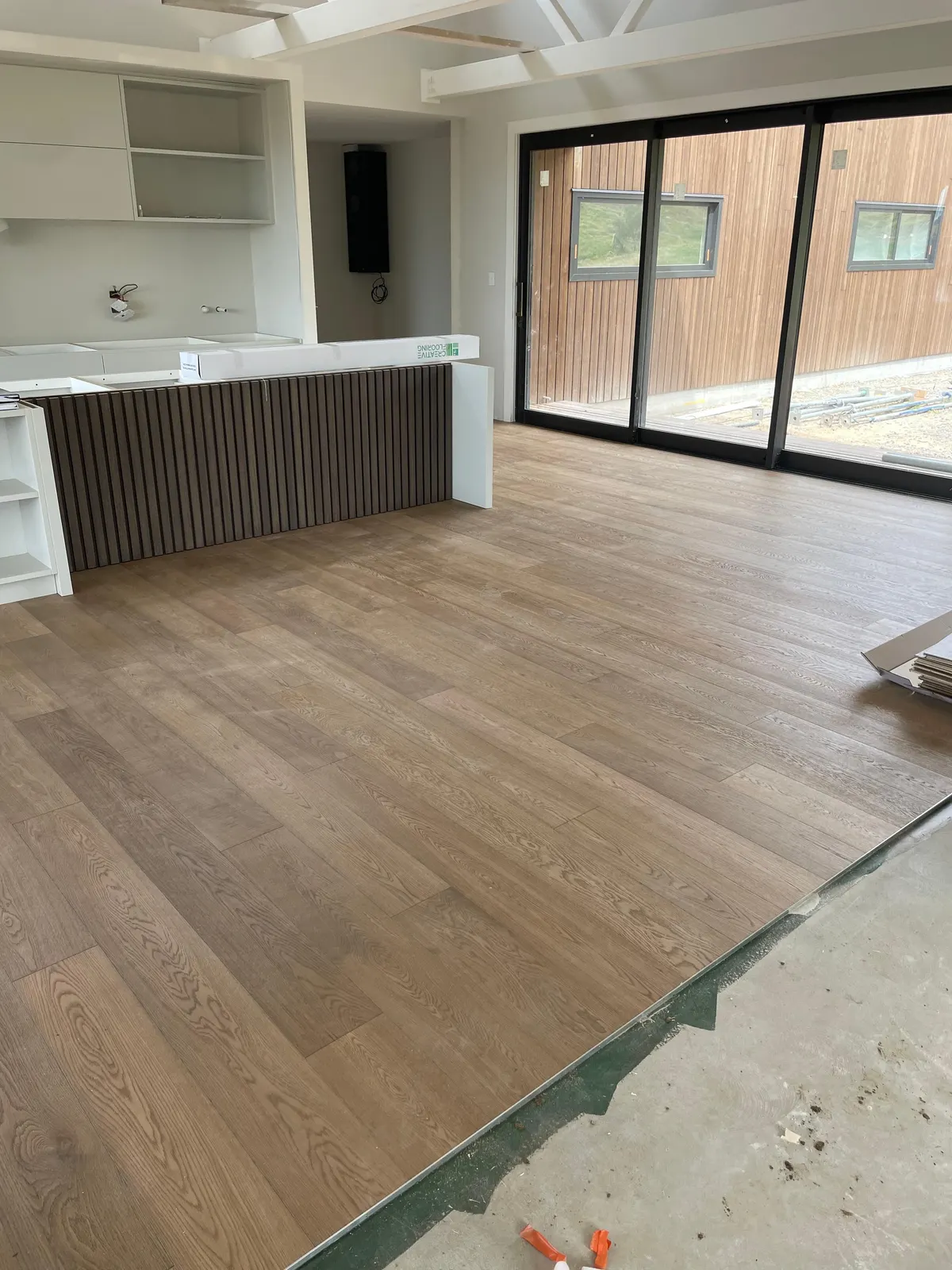 Timber floor through a kitchen and living area with black sliding doors