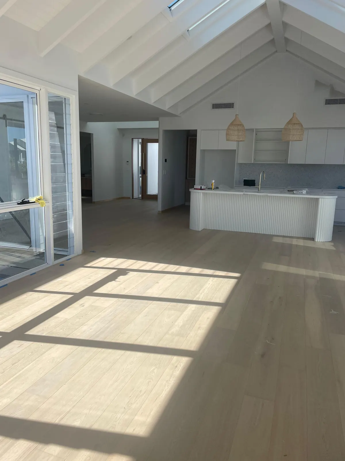 Pale timber floor in an open-plan living area with a raked ceiling